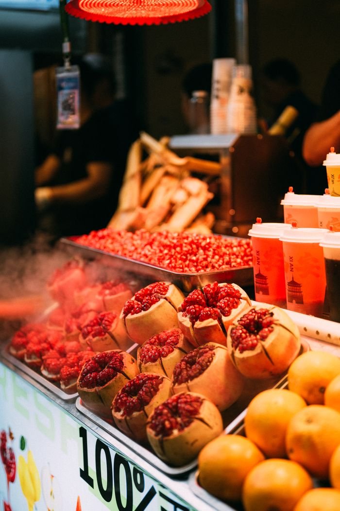Colorful street market stall with fresh pomegranates and juice under warm lighting, capturing a lively, inviting atmosphere.