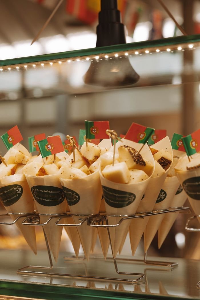 Delicious Portuguese street food served in cones with national flags in Porto market.